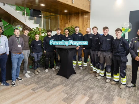 Powercomm staff holding a sign saying Powering Progress. Everyone is happy 