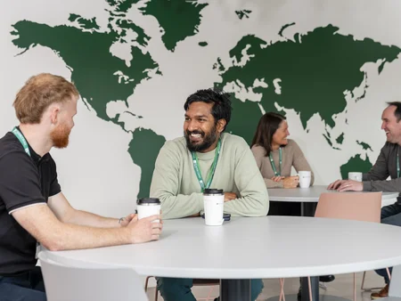 Staff in canteen chatting with picture of world map behind them