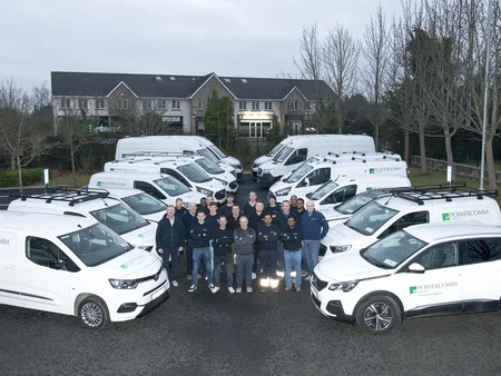A fleet of cars lined up on the left and right, with a group of Powercomm staff members standing in the middle during December 2024.