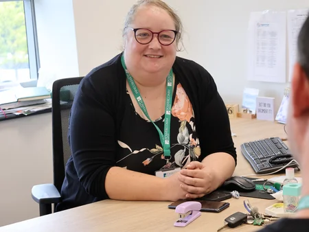 HR Manager in an office setting, smiling and speaking with a colleague