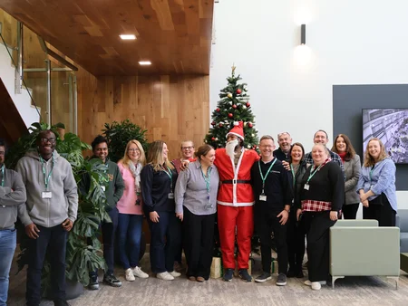 Staff from Powercomm Group standing together beside the tree with a staff member dressed as santa
