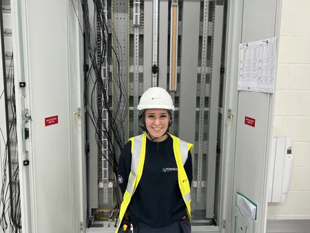 An apprentice electrician posing outside of a panel