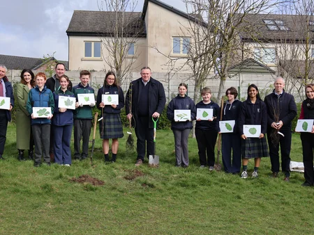 Group of teenagers and adults posing with trees at Scoil Mhuire Clane