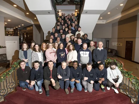 A large group of Powercomm staff members standing on a landing and staircase during Safety Day, December 2024.