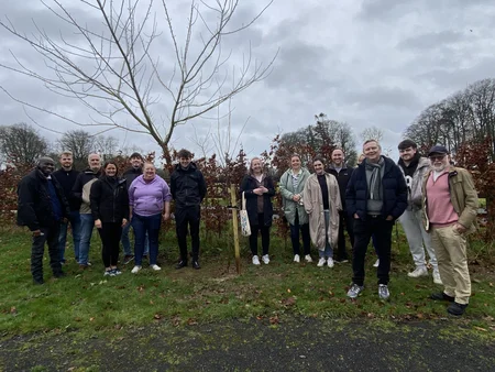 A group of Powercomm Employees smiling together as they plant a tree at Barretstown Camp