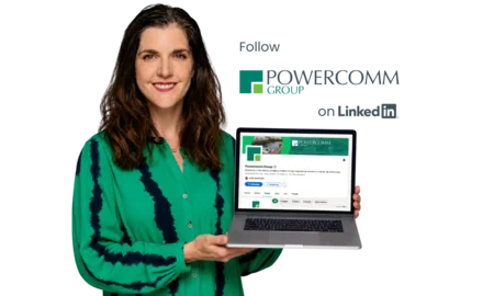 Aoife holding a laptop with Powercomm linkedin page on screen.