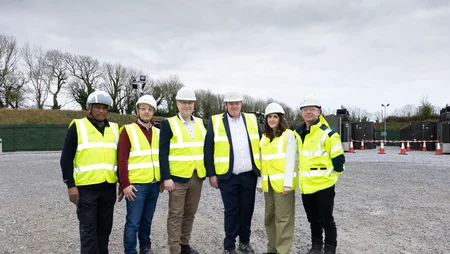 A group of Powercomm staff celebrating the ESB launch day of the BESS 2 project, wearing high-vis jackets and white hard hats. 