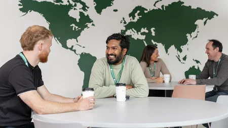 Staff in canteen chatting with picture of world map behind them