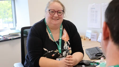 HR Manager in an office setting, smiling and speaking with a colleague