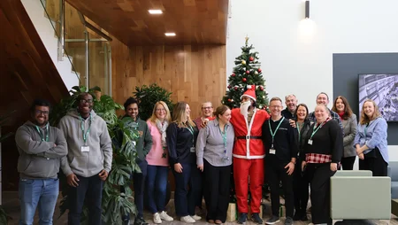 Staff from Powercomm Group standing together beside the tree with a staff member dressed as santa