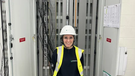 An apprentice electrician posing outside of a panel