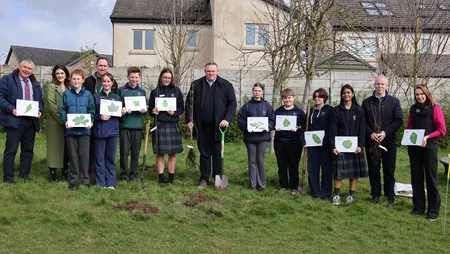 Group of teenagers and adults posing with trees at Scoil Mhuire Clane