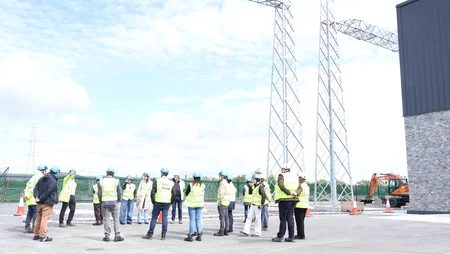 A group of people on site in Coolnabacky, looking up at steelworks