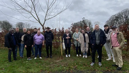 A group of Powercomm Employees smiling together as they plant a tree at Barretstown Camp